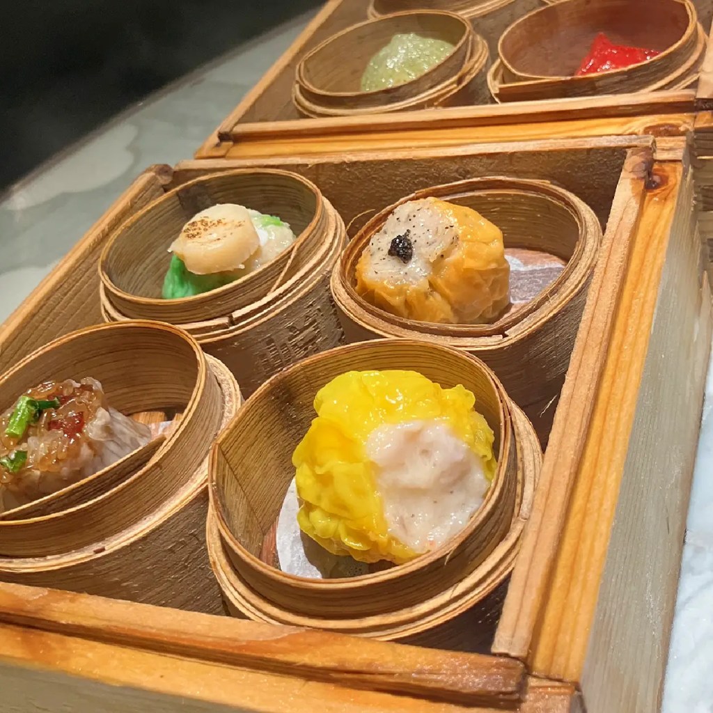 Steaming premium Hong Kong dim sum featuring colorful siu mai and dumplings in traditional bamboo baskets.